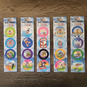 May include: Five vintage Walmart ICEE POGs, each with a unique circular design featuring cartoon characters in various action poses. The POGs are on long, rectangular cards with the Walmart and ICEE logos at the top. The background is a light blue with white clouds.