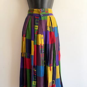 Könnte beinhalten: Ein bunter, mehrfarbiger, langer Rock mit geometrischem Muster. Der Rock hat einen Knopfverschluss und ist aus einem leichten Stoff gefertigt.