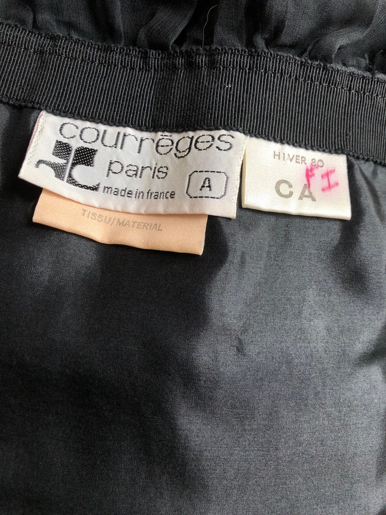 May include: A white tag with black text that reads "Courr&egrave;ges Paris made in France" and a size "A" tag. A white tag with black text that reads "HIVER 80 CA" and a pink handwritten "F1" tag.
