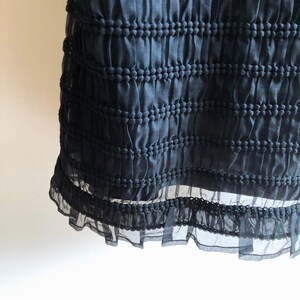 May include: Black skirt with a textured, gathered fabric and a ruffled hem.