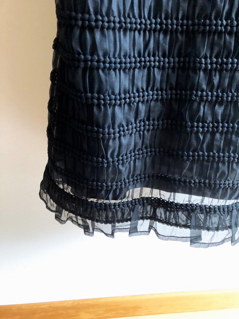 May include: Black skirt with a textured, gathered fabric and a ruffled hem.