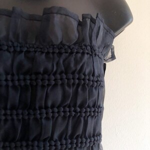 May include: A black strapless top with a ruffled neckline and a textured, gathered bodice.