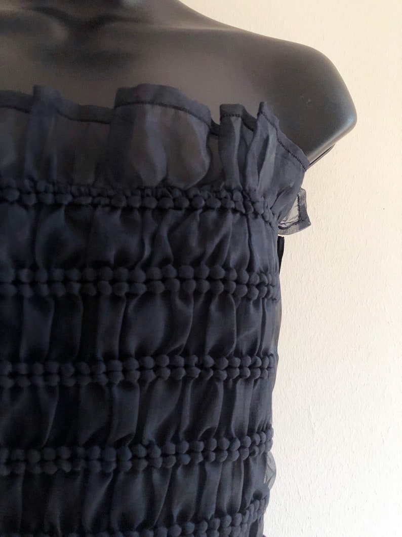 May include: A black strapless top with a ruffled neckline and a textured, gathered bodice.