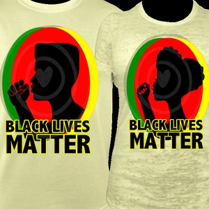 Pu&ograve; includere: Due magliette giallo chiaro con la scritta "BLACK LIVES MATTER". Ogni maglietta presenta una silhouette nera di una persona con il pugno alzato all'interno di un cerchio rosso, verde e giallo.