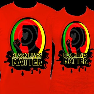Pu&ograve; includere: Due magliette rosse con le parole "BLACK LIVES MATTER" in giallo e nero. Ogni maglietta presenta una silhouette nera di una persona con il pugno alzato all'interno di un cerchio con strisce verdi, rosse e gialle.