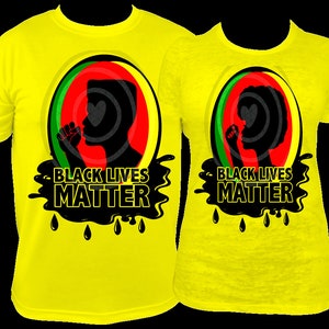 Pu&ograve; includere: Due magliette gialle con la scritta "BLACK LIVES MATTER" in nero. Ogni maglietta presenta una silhouette nera di una persona con un disegno a forma di cuore, su uno sfondo circolare rosso, verde e giallo.