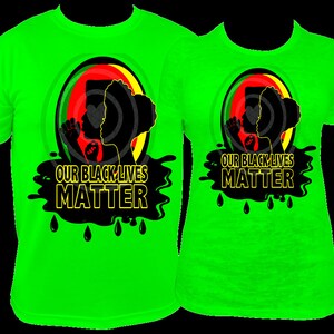 Pu&ograve; includere: Due magliette verde neon con la scritta "OUR BLACK LIVES MATTER". Le magliette presentano una grafica di due silhouette all'interno di un cerchio con colori rosso, giallo e verde. Gocce di vernice nera sotto il testo.