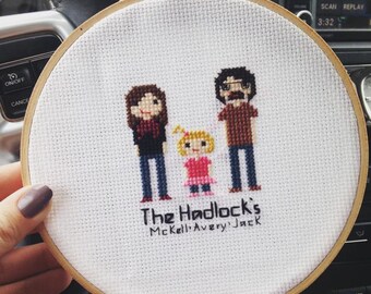 Peut inclure: Un cerceau de broderie blanc avec un motif de point de croix représentant un portrait de famille. Le motif représente un homme, une femme et un enfant. Le texte "The Hadlock's Mckell Avery Jack" est brodé sous la famille.