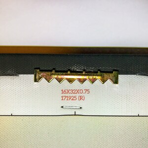 Pode incluir: Um gancho de metal dourado com uma borda dentada. O gancho est&aacute; preso a uma tela branca com o texto "16X32X0.75 171925 (R)" impresso em vermelho.
