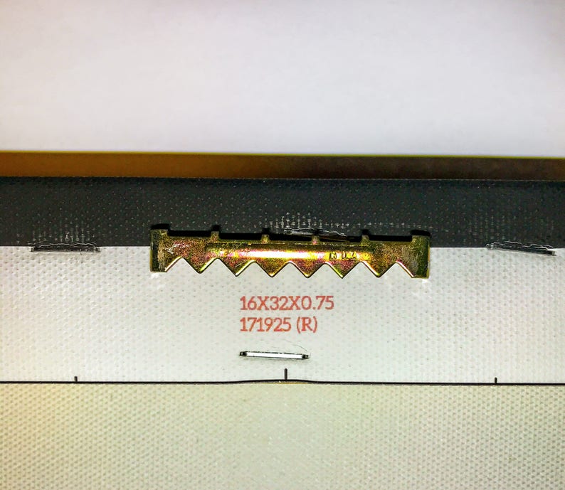 Pode incluir: Um gancho de metal dourado com uma borda dentada. O gancho est&aacute; preso a uma tela branca com o texto "16X32X0.75 171925 (R)" impresso em vermelho.