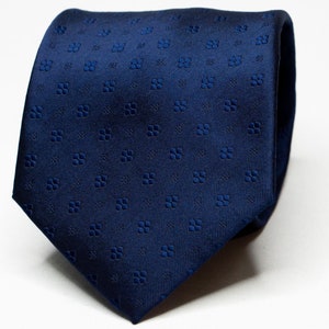 Peut inclure: Une cravate en soie bleu foncé avec un petit motif répété de trèfles à quatre feuilles.