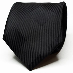 Może przedstawiać: Czarny jedwabny krawat o subtelnej fakturze żebrowanej.