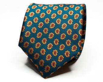 May include: A teal blue silk tie with a repeating pattern of small gold and red paisley shapes.