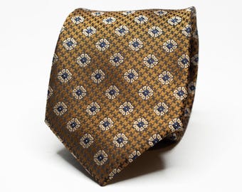 May include: A brown patterned tie with a geometric design featuring small white and blue squares. The tie is made of a silky material.