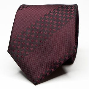 May include: A burgundy silk tie with a black geometric pattern. The tie has a diagonal stripe design.