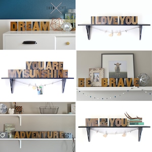 May include: Five shelves with wooden block letters spelling out different phrases, including "DREAM", "I LOVE YOU", "YOU ARE MY SUNSHINE", "BE BRAVE", and "ME & YOU". Each shelf has a string with small wooden hearts hanging from it.