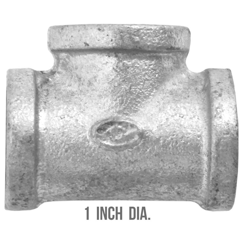 May include: A galvanized steel T-fitting with a 1-inch (2.54 cm) diameter. The fitting is T-shaped with a central opening and two side openings. The surface is textured and metallic grey. The text "1 INCH DIA." is printed below.