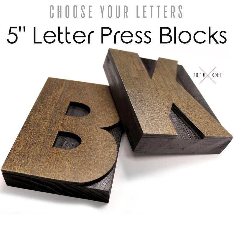 May include: Two wooden letterpress blocks, one with the letter "B" and the other with the letter "K". The blocks are 5 inches tall and have a dark brown stain with black edges.