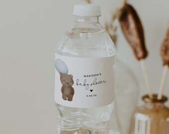 Peut inclure: Une bouteille d'eau en plastique transparente avec une étiquette blanche sur laquelle est inscrit "Madison's baby shower" avec un petit ours brun tenant un ballon bleu. La date "9.30.23" est imprimée sous le texte.