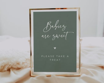 May include: A gold-framed sign with a sage green background and white text that reads "Babies are sweet" with a small heart symbol below the text. The sign also says "Please take a treat" in white text.