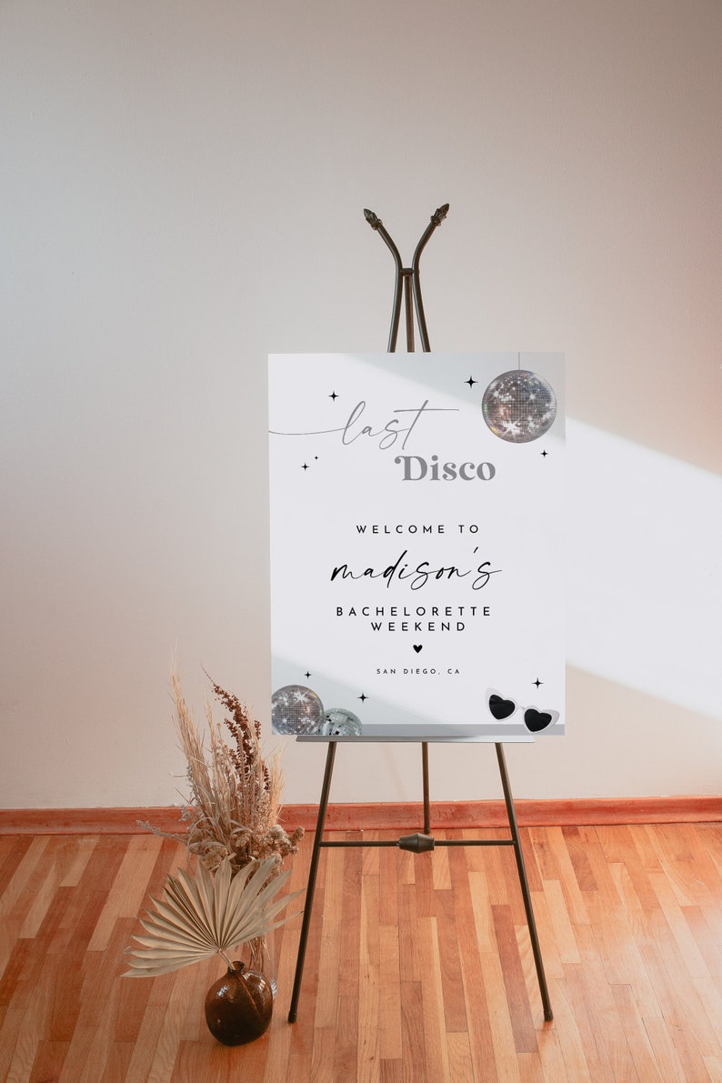 May include: White sign with black text that reads "last disco welcome to madison's bachelorette weekend san diego, ca" with a disco ball and sunglasses graphic.