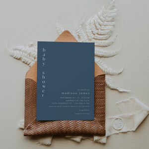May include: A blue baby shower invitation with white text. The invitation reads "baby shower" vertically on the left side and "in honor of madison james" at the top. The invitation includes the date, time, location, RSVP information, and registry details.