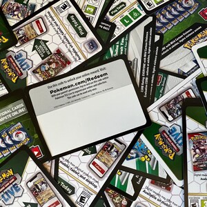 May include: A close-up of a stack of Pokemon Trading Card Game cards. The top card is a white card with black text that says "Use this code to unlock your online reward. Visit: Pokemon.com/Redeem".