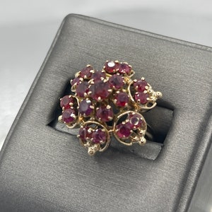 May include: A gold ring with a cluster of red gemstones set in a delicate filigree design.