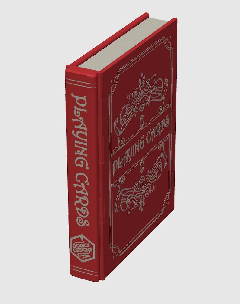 May include: A red playing card box with silver lettering and decorative flourishes. The spine reads "PLAYING CARDS" vertically. The front of the box also says "PLAYING CARDS" with decorative swirls. The bottom of the spine has a logo that says "DORKY DESIGNS".