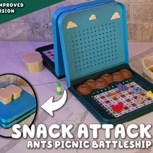 May include: A blue and green "Snack Attack Ants Picnic Battleship" game. The game board is open, revealing a grid with food-shaped game pieces, including donuts and a watermelon slice. The top of the game has a grid for tracking hits. Includes a small picnic basket.