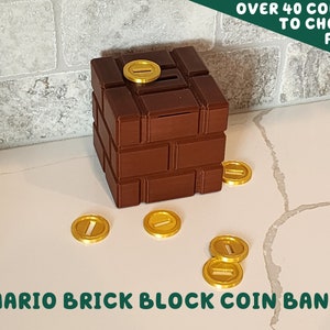 May include: A brown brick-style coin bank with a slot on top and gold-colored coins scattered around it. The text "MARIO BRICK BLOCK COIN BANK" is at the bottom. The text "OVER 40 COLORS TO CHOOSE FROM" is at the top.