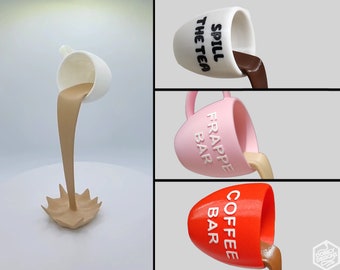 Può includere: Tre tazze in ceramica stampate in 3D con diverse smaltature e testi. Le tazze sono inclinate e sembrano versare un liquido. Il testo sulle tazze recita "Spill the Tea", "Frappe Bar" e "Coffee Bar".