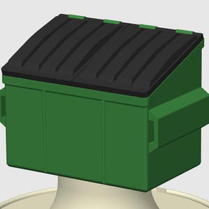 以下が含まれることがあります： 黒い蓋が付いた緑色のゴミ箱。ゴミ箱は長方形で、側面にハンドルが付いています。蓋はわずかに傾斜しており、一連の溝があります。ゴミ箱は白いベースの上にあります。
