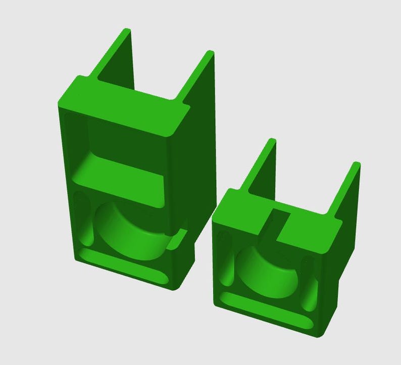 May include: Two bright green, three-dimensional, U-shaped brackets of varying heights. Each bracket features a rectangular base with a central circular cutout, a vertical slot, and two parallel upright arms extending from the top surface.