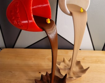 Può includere: Due tazze in ceramica con un liquido marrone e beige che ne fuoriesce. Il liquido è congelato in aria e forma uno schizzo sul fondo. Le tazze sono rosse e bianche.