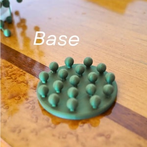 May include: A green base with a circular design featuring multiple small, round bumps. The base is labeled "Base" in white text.