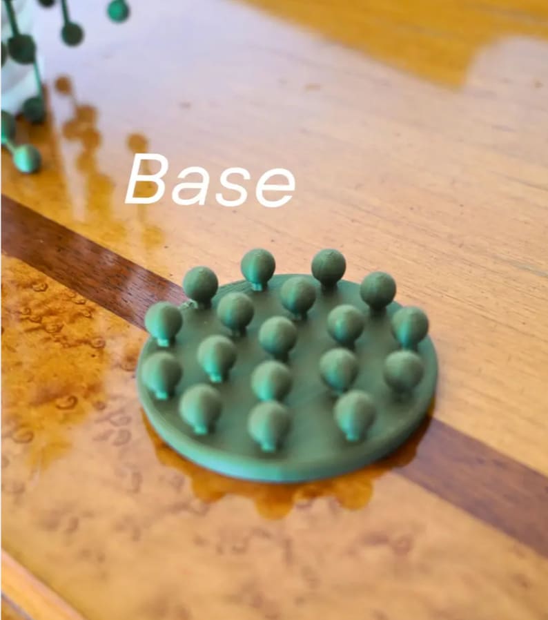 May include: A green base with a circular design featuring multiple small, round bumps. The base is labeled "Base" in white text.