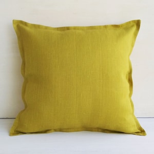 May include: A square, mustard yellow throw pillow with a linen texture.