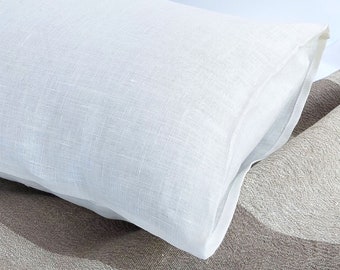May include: A white linen pillow with a subtle texture. The pillow is folded in half and placed on a brown and white striped fabric.