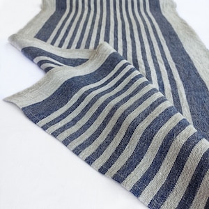 May include: A close-up of a blue and gray striped fabric. The fabric is woven with a linen texture and has a subtle sheen.