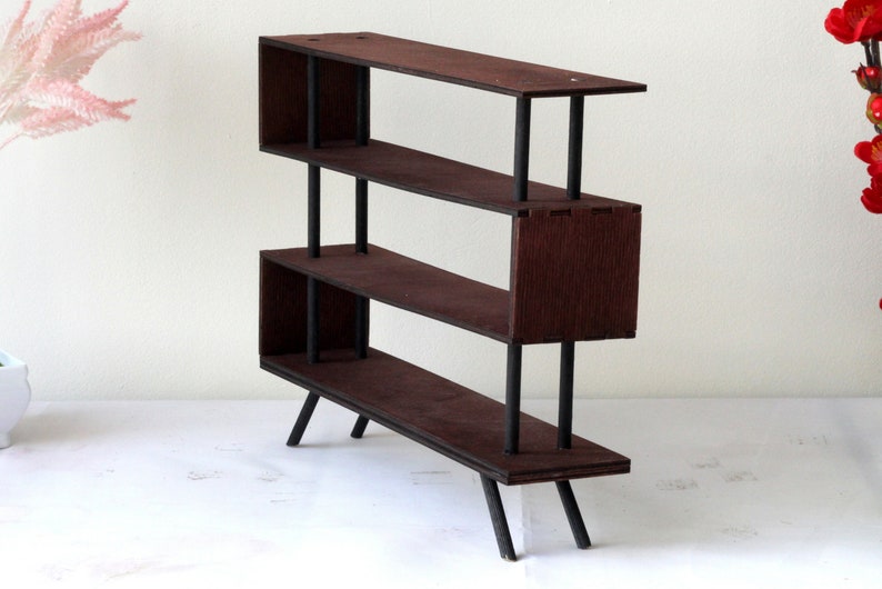 Puede incluir: Una estanter&iacute;a de madera marr&oacute;n oscuro con tres estantes y patas de metal negro. Los estantes est&aacute;n abiertos por delante y por detr&aacute;s, y la unidad es independiente.