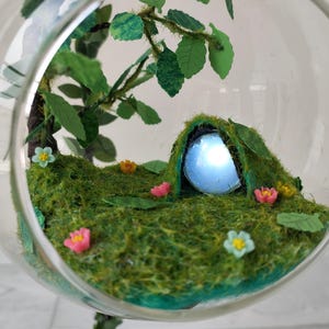 Hanging fairy garden with LED lighting. Metal hanger decorated with leaves flowers glass ball hill tree fairy cave inside Tabletop diorama