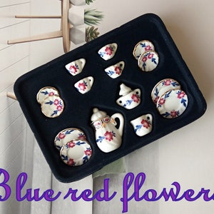 May include: A miniature tea set with a blue and white floral pattern. The set includes a teapot, creamer, sugar bowl, cups, and saucers. The set is displayed in a black velvet box.