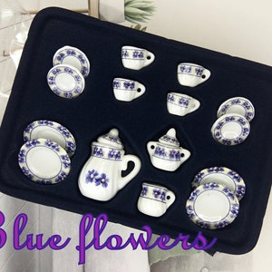 May include: A miniature tea set with blue floral designs. The set includes a teapot, creamer, sugar bowl, cups, and saucers. The set is displayed in a black velvet box.