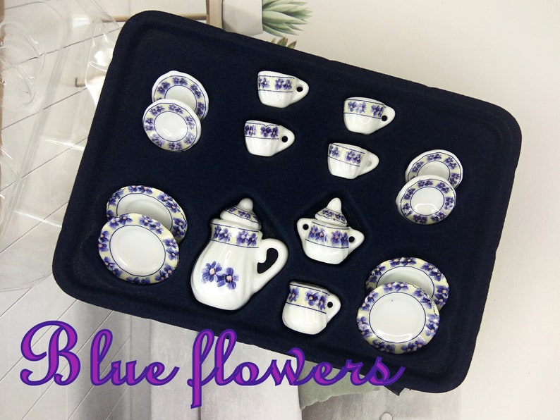 May include: A miniature tea set with blue floral designs. The set includes a teapot, creamer, sugar bowl, cups, and saucers. The set is displayed in a black velvet box.