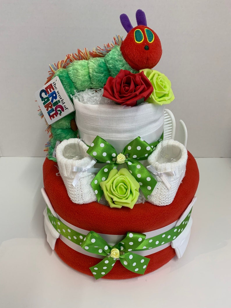 2 tier nappy cake in a hungry caterpillar theme made with nappies, red baby blanket, white muslin square, soft knit booties, brush set, hat, bib, scratch mittens and caterpillar soft toy. Gift wrapped with clear cellophane and ribbons and bow
