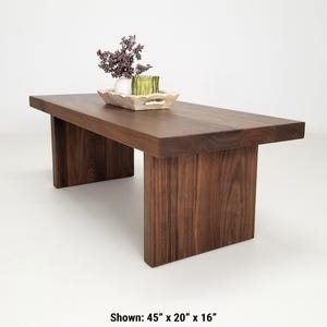 Solid walnut LILY coffee table with a thick slab top and panel legs, showcasing rich wood grain.