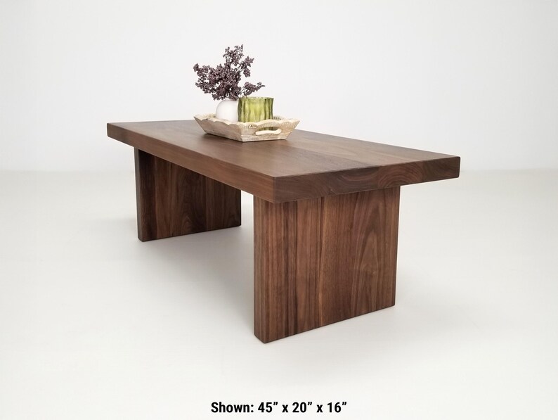 Solid walnut LILY coffee table with a thick slab top and panel legs, showcasing rich wood grain.