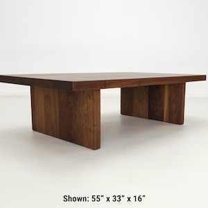 Solid walnut LILY coffee table with a thick slab top and panel legs, showcasing rich wood grain.