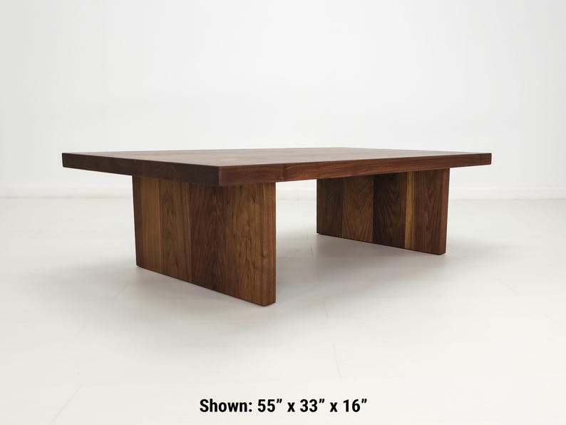 Solid walnut LILY coffee table with a thick slab top and panel legs, showcasing rich wood grain.